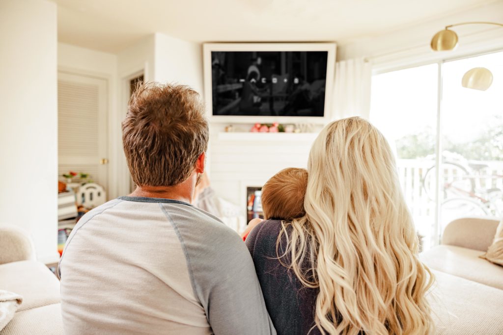 Family watching tv together while listening to the movie with wireless surround sound speakers